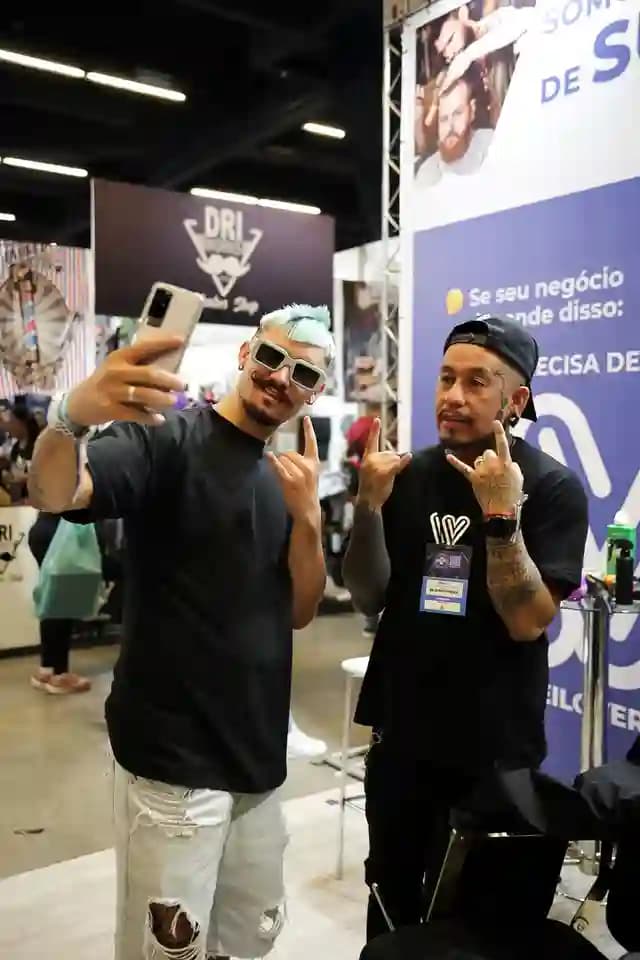 Barbeiros tirando uma selfie no estande da WeiBook na Barber Week de São Paulo, Brasil