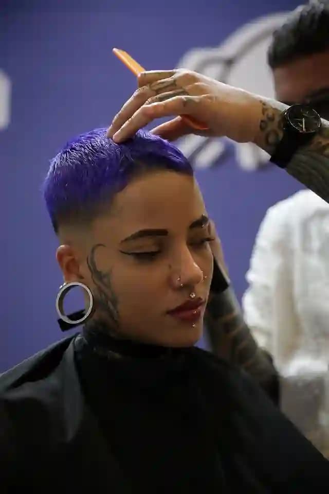 Estilista fazendo um corte em uma cliente de cabelo colorido na feira Belleza y Salud de Bogotá, na Colômbia
